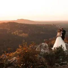 Fotografka uwiecznia parę młodą na tle jesiennego krajobrazu. Warto wiedzieć, ile kosztuje godzina pracy fotografa, by mieć takie wspomnienia.