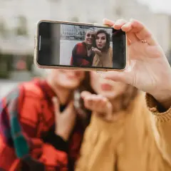 Dwie kobiety robią sobie selfie telefonem na tle miasta.