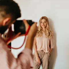 Fotograf robi zdjęcie uśmiechniętej blondynce. Zastanawiasz się, ile fotograf bierze za sesję?