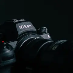 Ciemne zdjęcie aparatu Nikon z obiektywem, z widocznym logo.