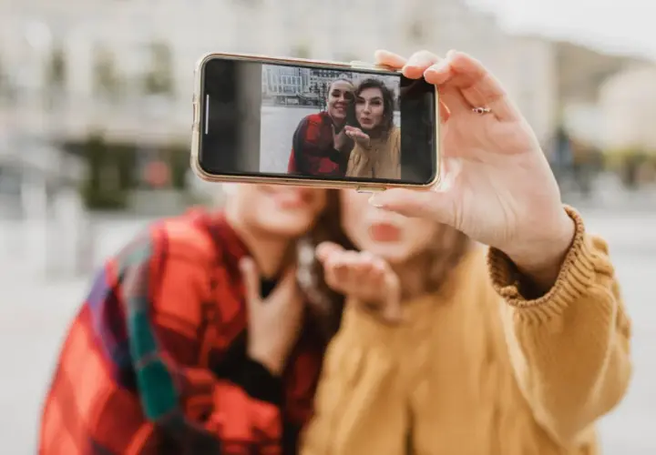 Dwie kobiety robią sobie selfie telefonem na tle miasta.