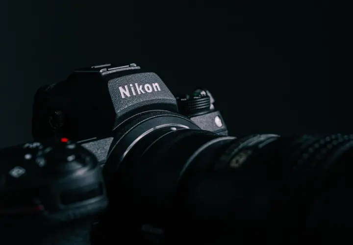 Ciemne zdjęcie aparatu Nikon z obiektywem, z widocznym logo.