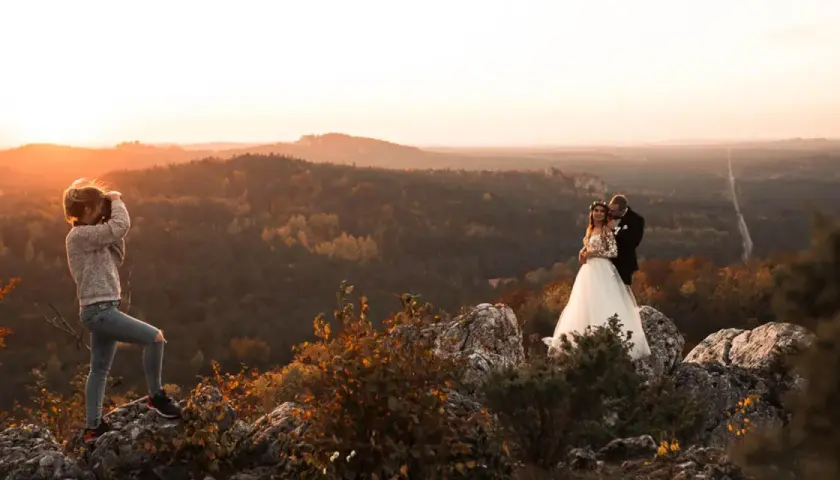 Fotografka uwiecznia parę młodą na tle jesiennego krajobrazu. Warto wiedzieć, ile kosztuje godzina pracy fotografa, by mieć takie wspomnienia.