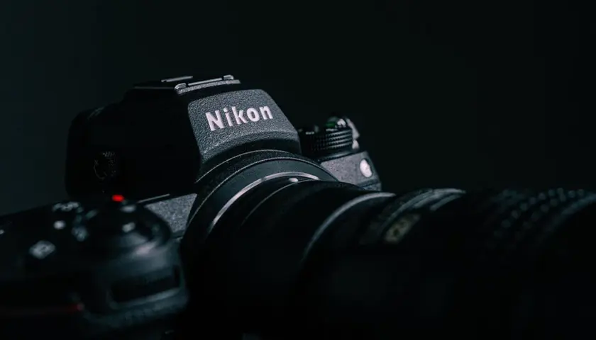 Ciemne zdjęcie aparatu Nikon z obiektywem, z widocznym logo.