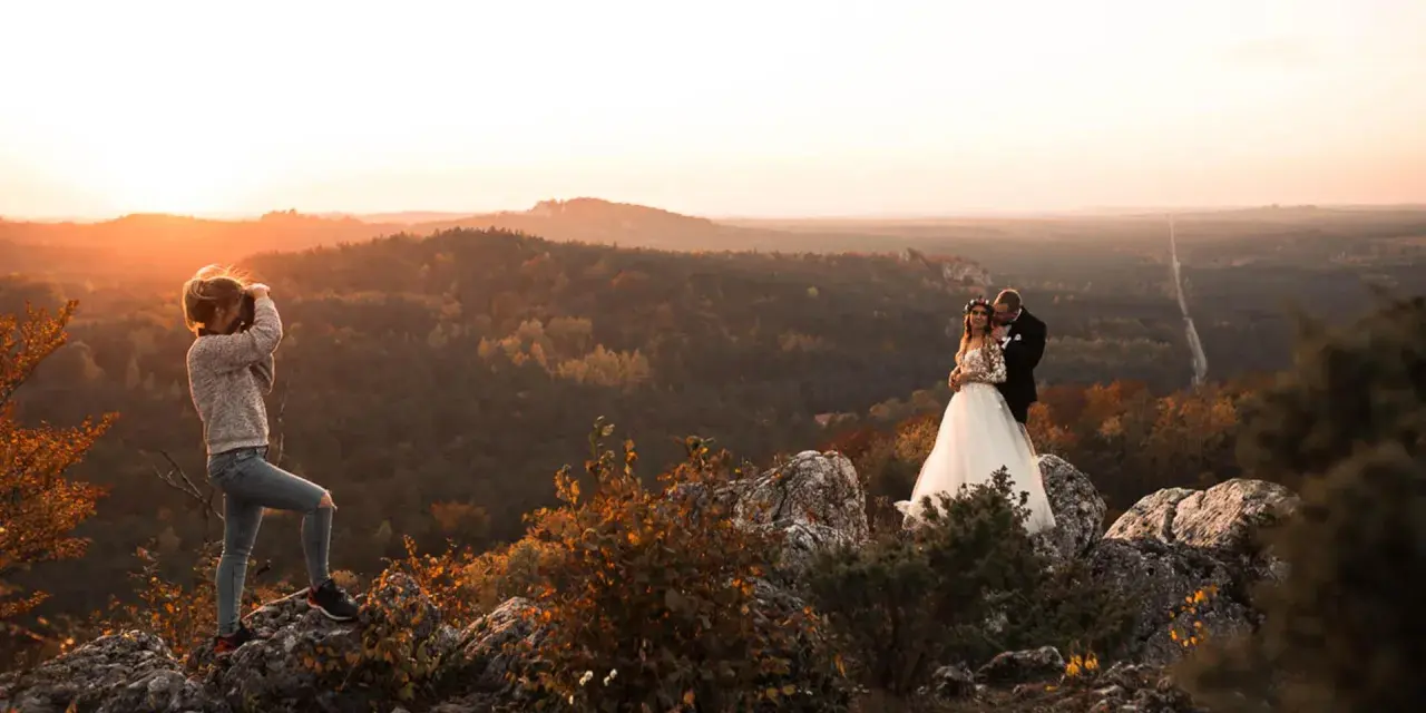 Fotografka uwiecznia parę młodą na tle jesiennego krajobrazu. Warto wiedzieć, ile kosztuje godzina pracy fotografa, by mieć takie wspomnienia.