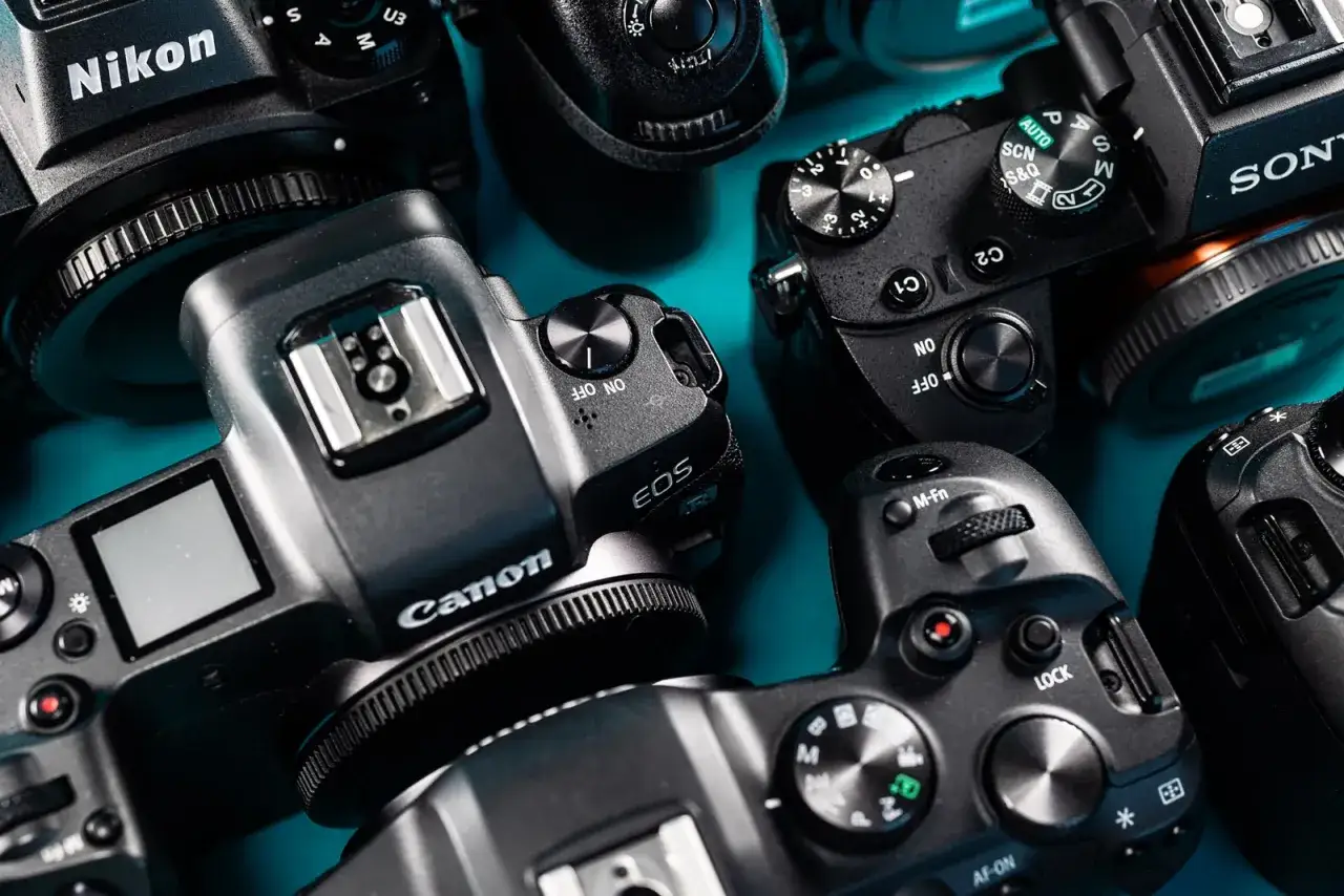 Stos różnych aparatów fotograficznych marek Canon, Nikon, Sony. Jaki wybrać?